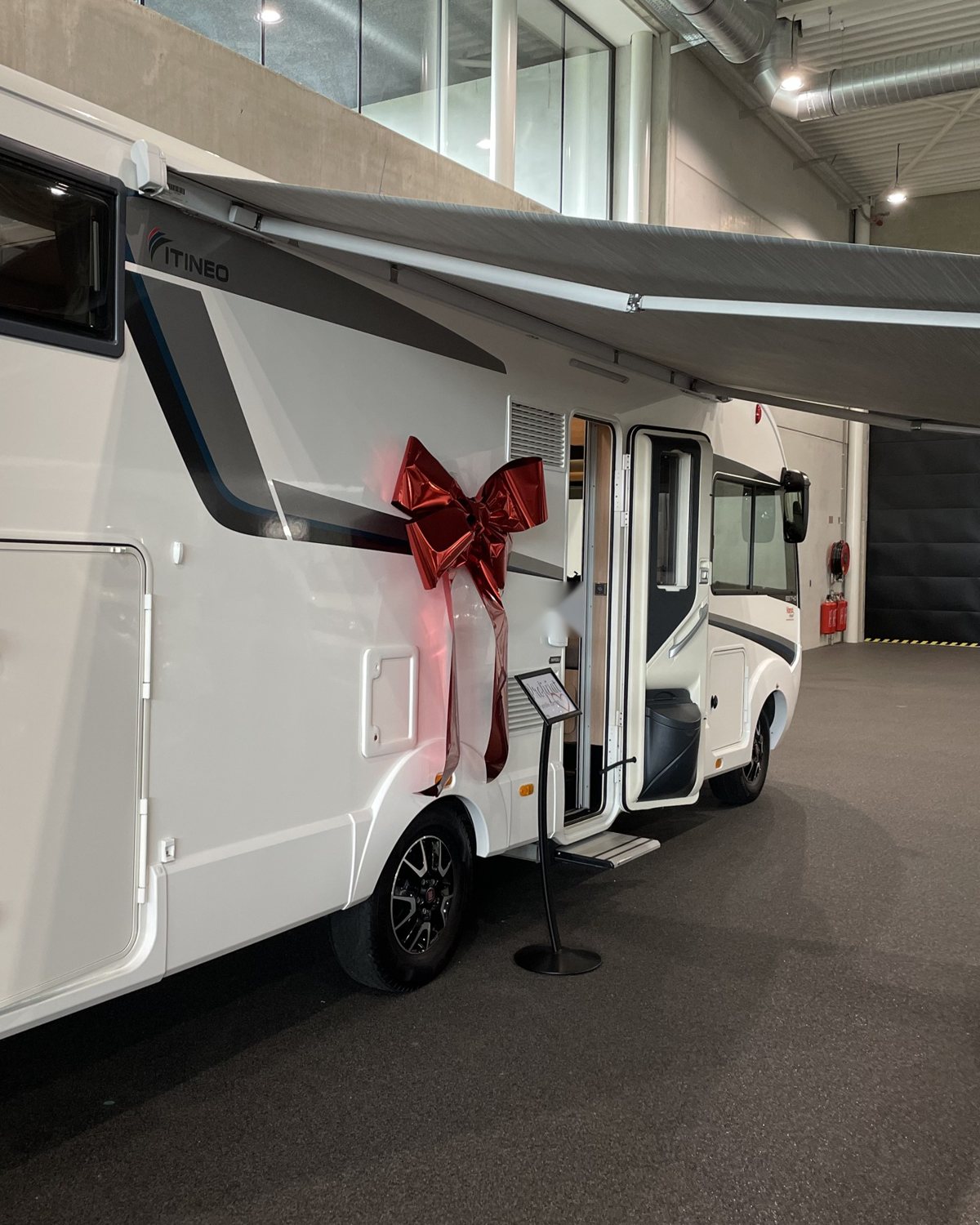 Een nieuwe camper in de showroom, klaar voor aflevering, met een rode strik op de deur