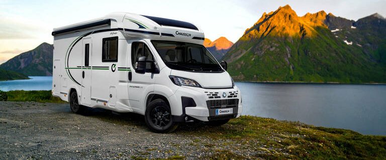 Een camper aan een bergmeer, de toppen in het laatste zonlicht